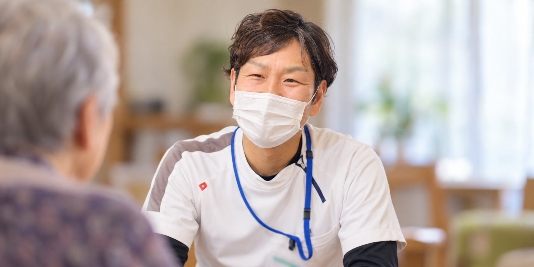 利用者さまと目線を合わせて話を聞く理学療法士のイメージ